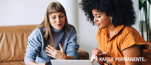 Two young businesswomen having a discussion while looking at a laptop screen. Two female entrepreneurs working as a team in a modern workplace.